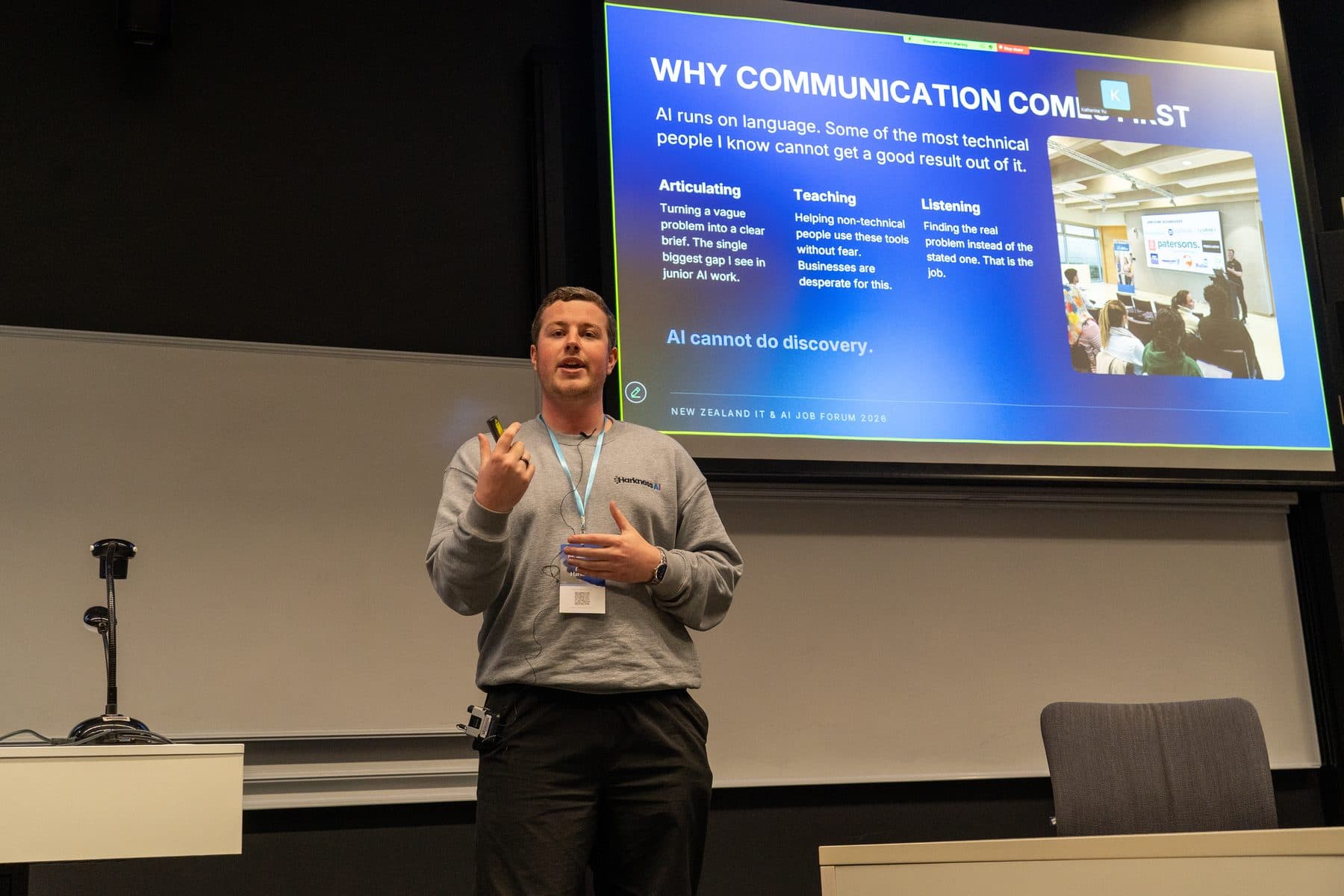 Blake Harkness gesturing beside a slide titled "Why communication comes first" at the NZ IT and AI Job Forum
